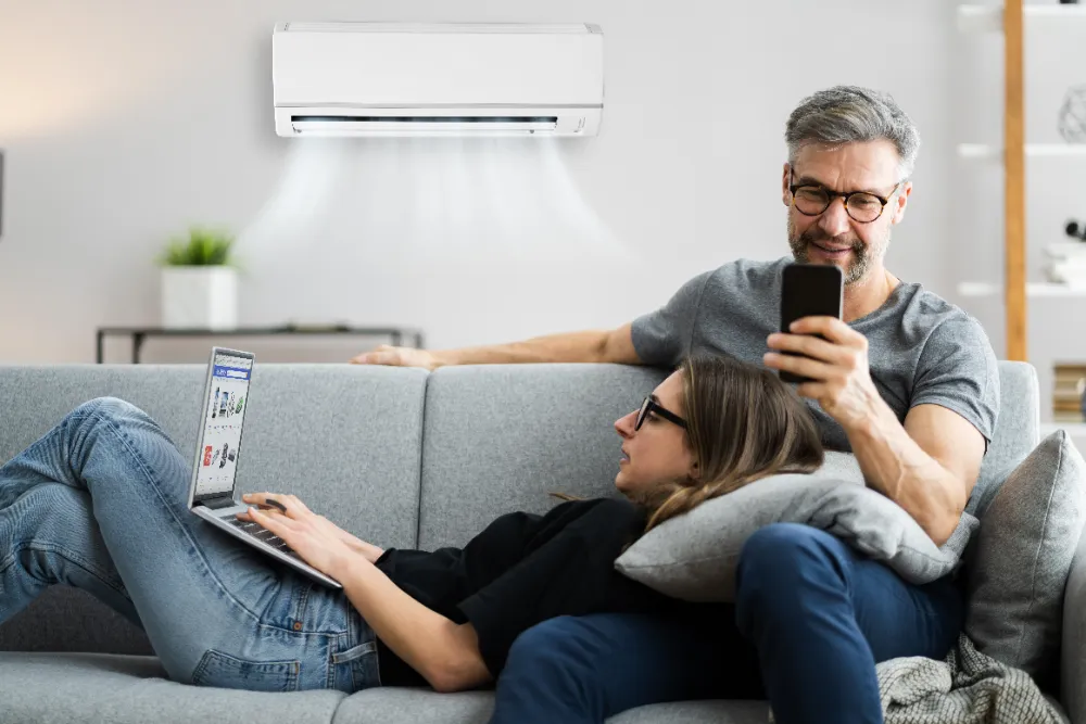 couple sitting on sofa with ductless unit on the wall behind them